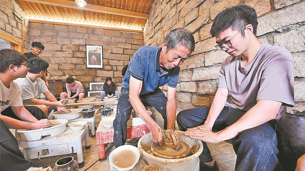 萌源制硋世家第七代传人肖家涨向前来参观研学的学生演示拉坯制硋技艺